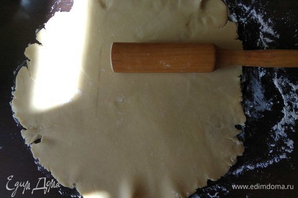 Разогреваем духовку до 180°C. Достаем тесто и на присыпанной мукой поверхности тонко раскатываем в круг.