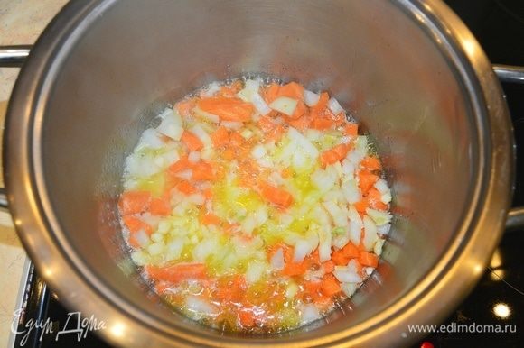 В разогретую кастрюлю с маслом добавить лук, чеснок, морковь, перемешать, тушить несколько минут.