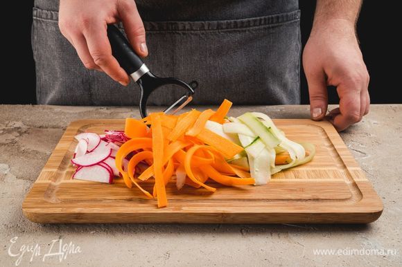 Морковь и огурцы очистите, нарежьте слайсами при помощи овощерезки. Редис нарежте тонкими полукольцами.