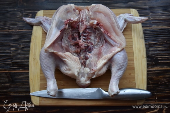 Цыпленка разрезать вдоль по грудке и раскрыть тушку.