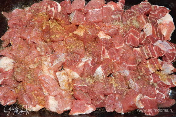 Мясо моем, режем средними кусочками. Форму для запекания смазываем подсолнечным маслом, выкладываем мясо, солим, перчим, добавляем хмели-сунели и приправу для мяса.