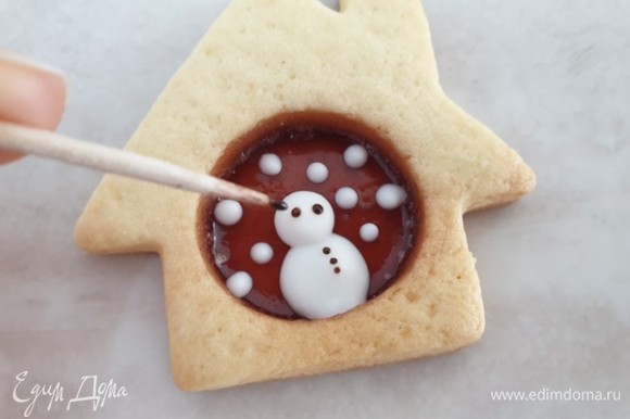 Растопите шоколад в микроволновой печи. Когда глазурь подсохнет, обмакните зубочистку в шоколад и нарисуйте снеговику глазки и пуговицы на теле. Можно также нарисовать улыбку.