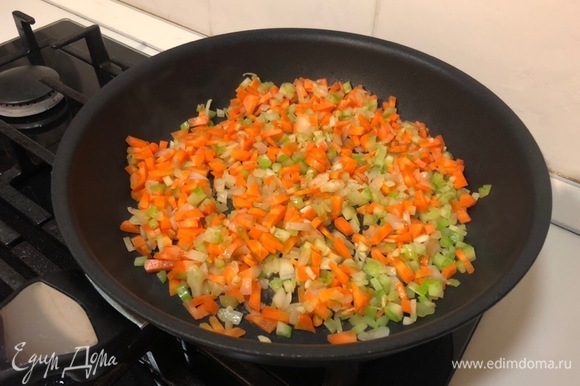 После добавляем остальные овощи — морковь и один стебель сельдерея. Перемешиваем, убавляем огонь до минимума и тушим минут 15 до мягкости овощей.