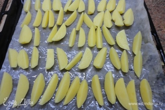 Очищенный и нарезанный дольками картофель выкладываем на смазанный маслом лист, не солим. Запекаем в духовке до готовности.