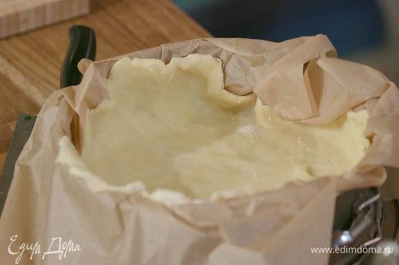 Разделить тесто на две неравные части, большую раскатать на бумаге для выпечки и поместить в разъемную форму, так чтобы получились высокие бортики, затем отправить в морозильник.