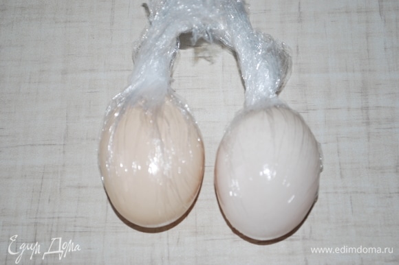 Тщательно вымойте два куриных яйца, оберните их пищевой пленкой.