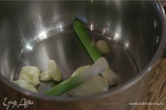 В глубокую кастрюлю выложить сливочное масло, весь чеснок и влить немного горячей воды.