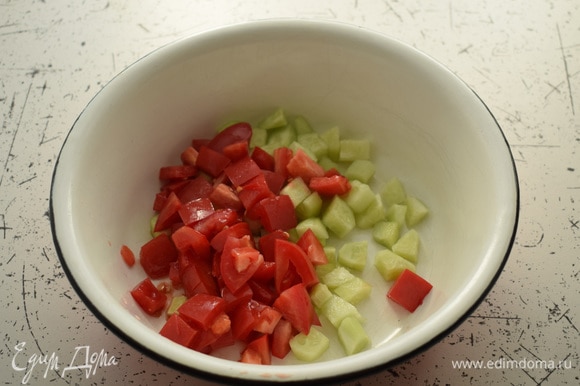 Огурцы очистить и нарезать кубиками. Нарезать помидоры. Выложить овощи в большую миску.