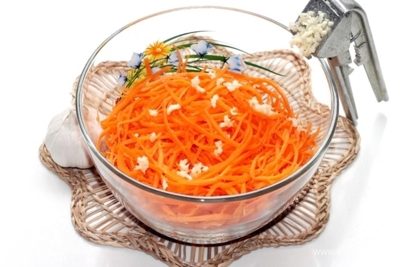 Зубчики чеснока очистить и спрессованными добавить к моркови. Растительное масло нагреть в небольшой емкости и в раскаленном виде вылить сверху на чеснок, перемешать. И в конце готовки добавляем лимонный сок.