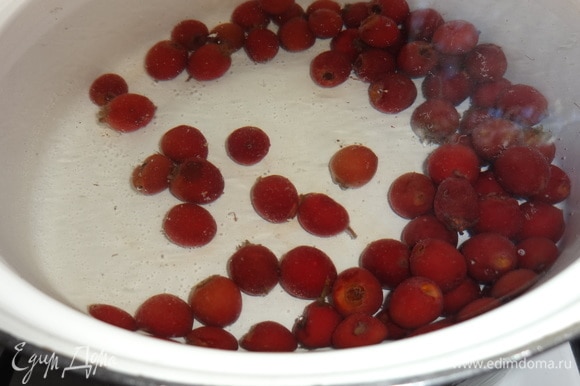 В кастрюлю налить воды, положить ягоды боярышника. У меня замороженные. Если свежие, то их надо вымыть, обрезать плодоножки. Довести до кипения, убавить огонь до среднего и варить боярышник 15–20 минут.