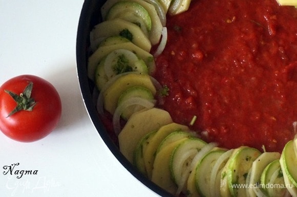 Приготовить соус: 5 помидоров измельчить в блендере или натереть на терке. Одну столовую ложку томатной пасты развести в небольшом количестве воды. Положить помидоры и томатную пасту в кастрюлю и довести до кипения. Добавить красный острый перец по вкусу. Взять большую круглую сковороду или форму для выпекания. На дно вылить томатный соус.