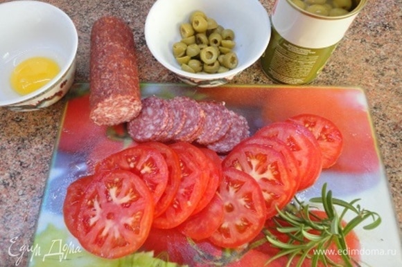 Помидоры, салями и оливки нарежьте кружочками. Включите духовку на разогрев до 200°C.