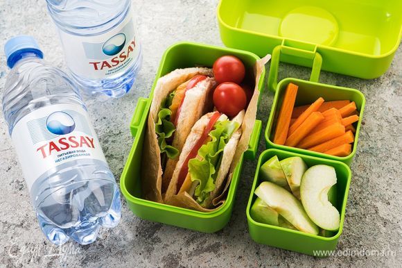 Положите сэндвичи в контейнер, добавьте бутылку негазированной воды Tassay и контейнеры с морковными палочками и кусочками яблок — питательная и сытная ссобой для ребенка готова!