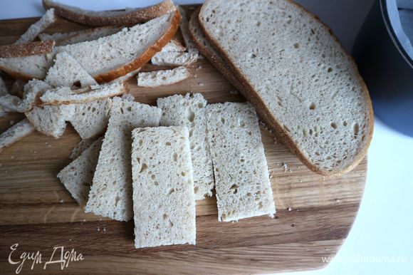 Срезать корки с кусочков хлеба, нарезать на прямоугольники шириной примерно 3 см. Длина прямоугольных пластинок из хлеба — на ваше усмотрение, но советую не делать шарлотку очень высокой, так как нужно сохранить стабильность начинки. Я делала пластины из хлеба длиной 4 см.