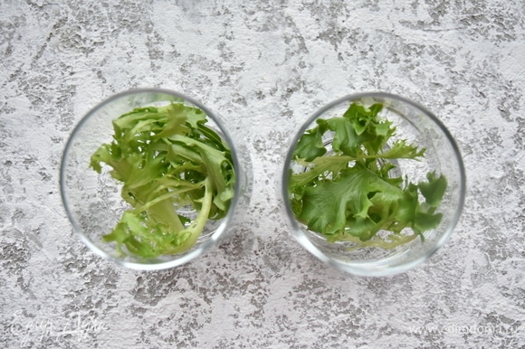 Для оформления салата подготовить стеклянные бокалы. Листья салата хорошо промыть и тщательно просушить. На дно бокалов выложить веточки салата.
