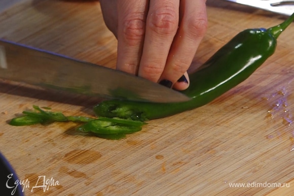 Мелко нарезать зеленый перец чили, убрать семена. Чили и сладкую паприку добавить в сковороду.