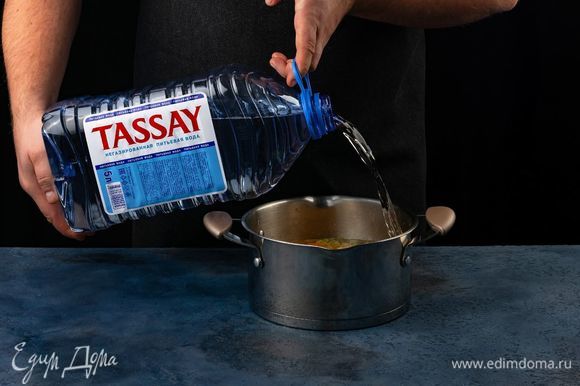 Залейте водой Tassay. Добавьте в кастрюлю фасоль и тертые помидоры.