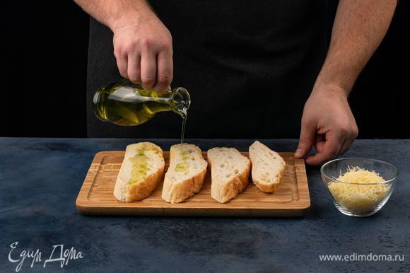 Сыр натрите на крупной терке. Хлеб нарежьте на ломтики, полейте оливковым маслом.