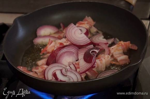 Красный лук почистить, нарезать полукольцами, добавить в сковороду с беконом и обжарить все вместе.