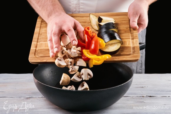 Нарежьте на кусочки болгарский перец, баклажан и грибы, отправьте все на сковороду и обжарьте на растительном масле.