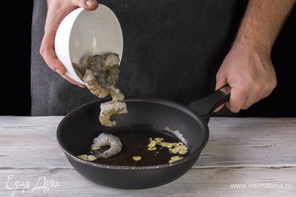 На сковороду налейте масло и обжарьте чеснок. Добавьте креветки и обжаривайте до готовности 3 минуты.