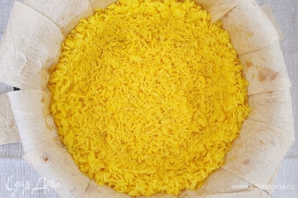 Выкладываем на лаваш половину риса. Слегка примнем рис таким образом, чтобы получилась чаша с бортиками. Во время запекания мясо и сухофрукты не должны касаться лаваша.