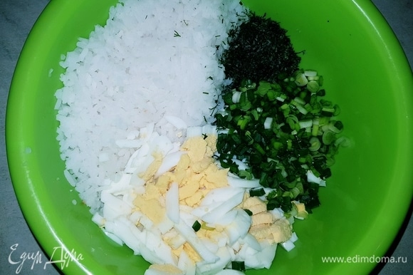 В чашку выкладываем отварной рис, отварные и нарезанные яйца (3 шт.), мелко нарезанные укроп и зеленый лук.