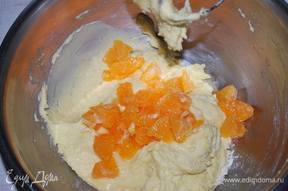 В готовое тесто добавьте мандарины, очищенные от пленок, мелко их резать не надо.