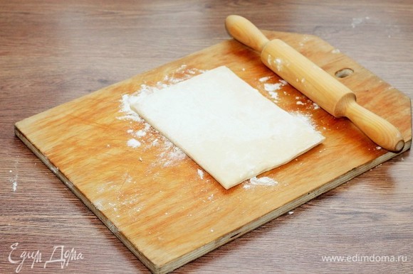 Размороженное слоеное тесто выложить на подпыленную мукой разделочную доску и раскатать до увеличения в длине в 2 раза.