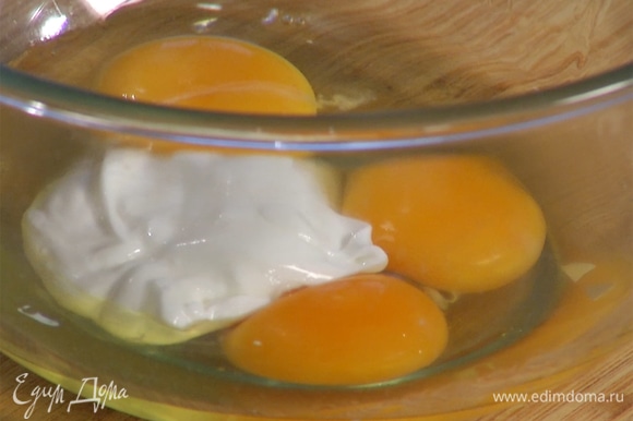 В отдельной миске венчиком смешать яйца и йогурт, затем медленно влить оливковое масло, продолжая вымешивать, пока не получится однородная, гладкая масса.