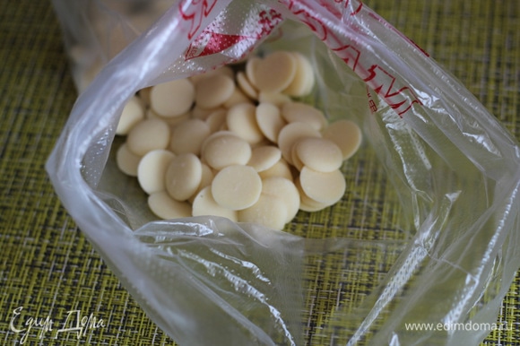В кондитерский мешок насыпать кусочки белого шоколада, добавить несколько капель красителя.