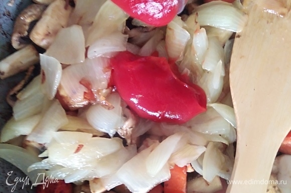 К грибам с морковкой добавить лук и томатную пасту, посолить.