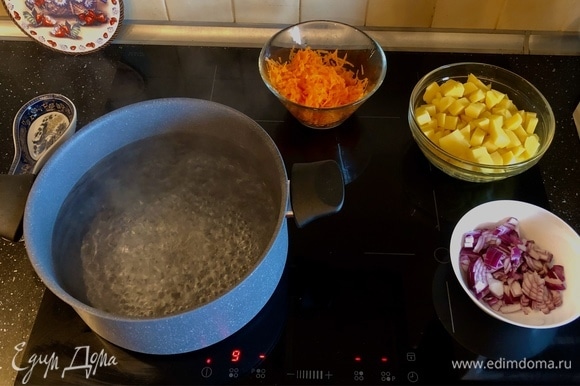 Добавить картофель, морковь и лук в кипящую воду.