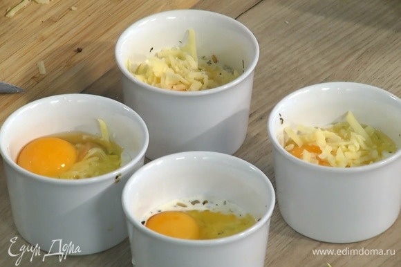 В каждую форму разбить по яйцу, так чтобы желток не растекся, посыпать оставшимся сыром.