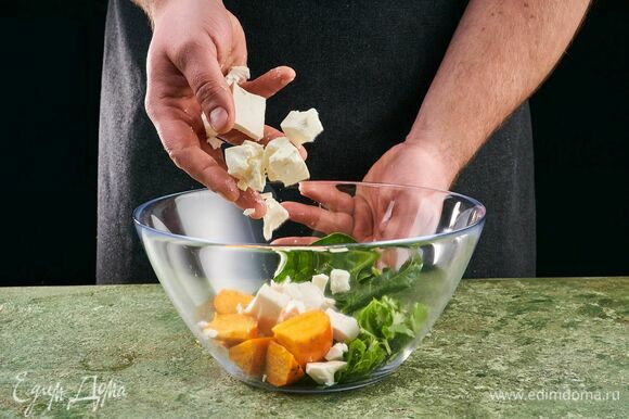 Выложите в салатник шпинат, кинзу, кусочки хурмы и козьего сыра.