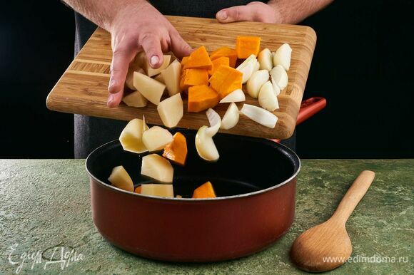 В сотейник с растительным маслом выложите тыкву, картофель и лук. Обжарьте слегка до румяной корочки.
