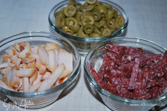 Оливки нарежьте колечками, колбасу и куриную грудку — соломкой. Можно добавить любые копчености или мясо по своему вкусу.