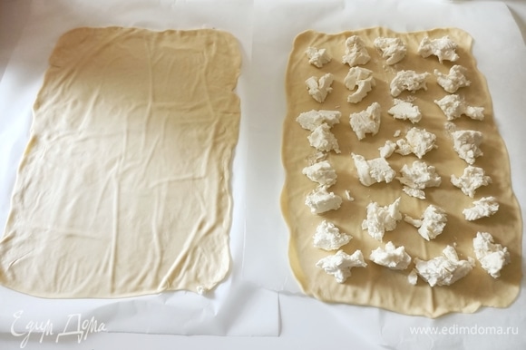 Достаем тесто, снова вымешиваем. Выкладываем на пергаментную бумагу и очень тонко раскатываем, должно получиться два прямоугольника одинакового размера. На один кладем сыр.