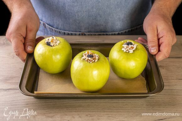 Нафаршируйте яблоки. Выложите яблоки в форму и запекайте при 140℃ около 15 минут.
