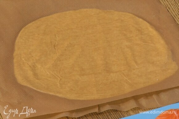 Охлажденное тесто разрезать пополам и раскатать между листами для выпечки в тонкие пласты.