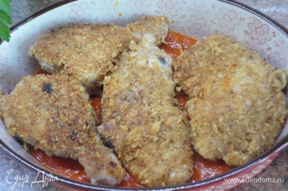Половину томатного соуса выложить на дно формы для запекания, а сверху — кусочки курицы.