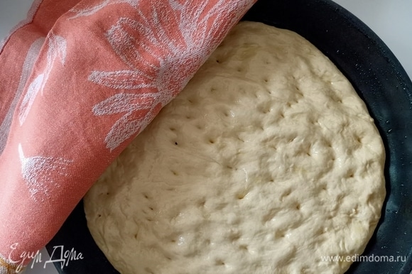 Форму смазать оливковым маслом. Выложить тесто и руками распределить по дну формы, делая пальцами небольшие вмятины. Накрыть полотенцем и дать постоять еще 30–40 минут.