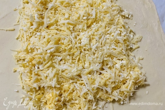 Натираем сыр на крупной терке. Можно использовать несколько разных сортов. Если сыр не достаточно соленый, его можно посолить. Натертый сыр распределяем по центру и немного по краям.