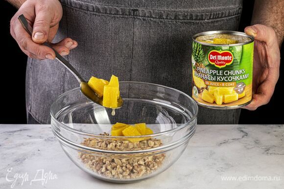 Откройте банку с ананасами Del Monte (435 г), слейте сок и выложите кусочки ананаса в чашу к орехам.