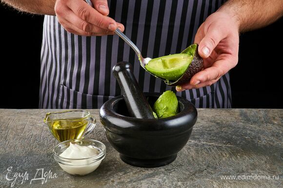 Авокадо очистите и тоже переложите в ступку. Добавьте сметану и оливковое масло.