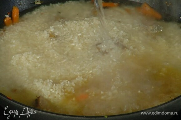 Рис промыть, всыпать в сковороду к мясу и, не перемешивая, равномерно распределить, затем влить кипяток, так чтобы рис был покрыт на 1–2 см.