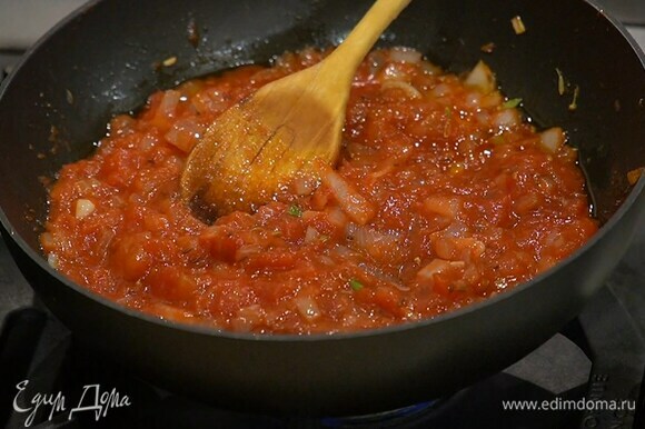 Когда лук станет прозрачным, ввести томатную пасту, перемешать и немного прогреть, затем добавить консервированные помидоры и еще немного прогреть, палочку корицы удалить.