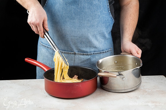 В сковороду с беконом добавьте спагетти.