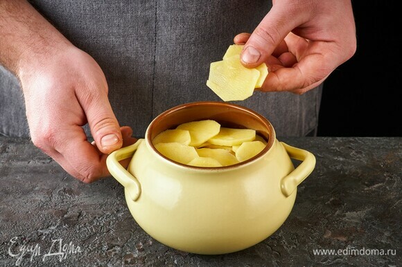 Верхним слоем выложите картофель. Накройте крышкой и поставьте в духовку, разогретую до 180°C, на 45 минут.