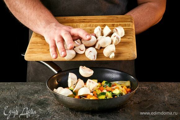 Нарежьте грибы кусочками и добавьте к овощам. Обжаривайте около 15 минут.
